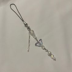 a white necklace with butterfly charms on it's end and a chain attached to it