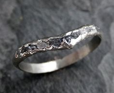 a close up of a silver ring on a black stone surface with some rocks in the background