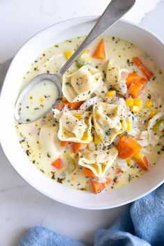 a white bowl filled with pasta and veggies next to a blue napkin on top of a table