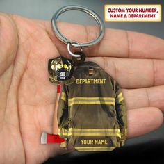 a fireman jacket keychain is being held in someone's hand with the caption, custom your number, name & department