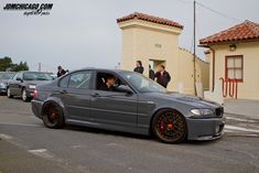 a gray car parked in front of a building with people looking out the window at it