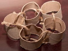 several rolls of toilet paper tied with twine on a wooden table top, ready to be used as candlesticks