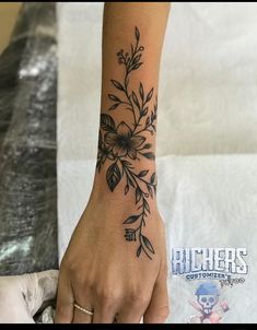 a woman's hand with a flower tattoo on it