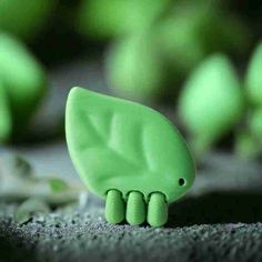 a small green toy elephant sitting on top of a black surface with other toys in the background