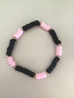 a black and pink beaded bracelet with gold accents on a white tablecloth background