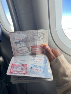 someone is holding up their passport in front of an airplane window with the wing visible