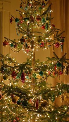 a christmas tree with ornaments and lights in the shape of an ornament on it