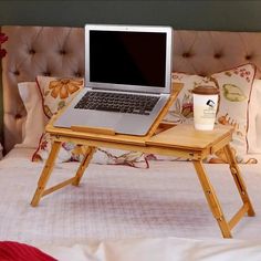 a laptop computer sitting on top of a wooden table next to a cup of coffee