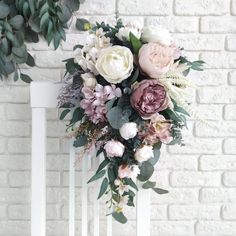 a bouquet of flowers sitting on top of a white chair next to a brick wall