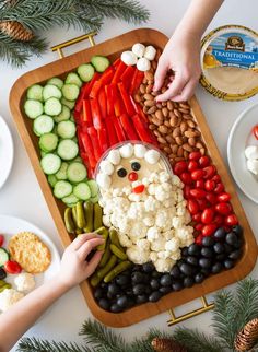 a platter filled with vegetables and veggies next to a person making a santa face