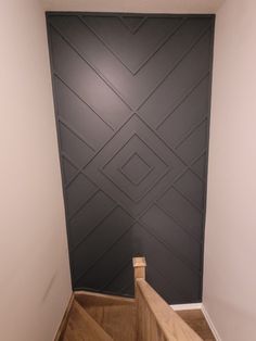 an empty room with stairs leading up to a wall that is painted black and white