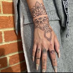 a woman's hand with tattoos on it and a flower tattooed on the wrist