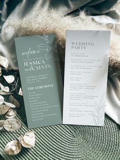 two wedding programs sitting on top of a bed next to silver foil flowers and leaves