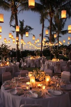 an outdoor dining area with lit lanterns and tables set up for a formal function at dusk