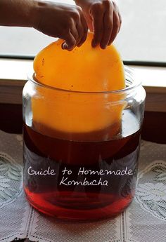 someone is pouring liquid into a jar with an orange in it and the words cuddle to homemade kombucha written on it