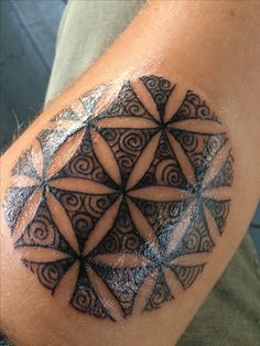 a man with a tattoo on his arm has a geometric design in the shape of a flower