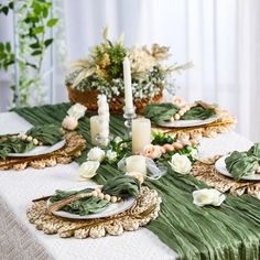 the table is set with green and white flowers, candles, and napkins on it