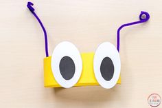 a paper bag with googly eyes and purple string attached to it on a table