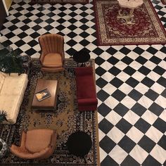 an overhead view of a living room with black and white checkered flooring, two couches, chairs, coffee table and rugs