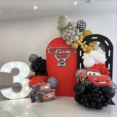 the birthday cake is decorated with cars and balloons