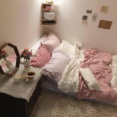 a bed with pink and white sheets on top of it next to a table filled with flowers