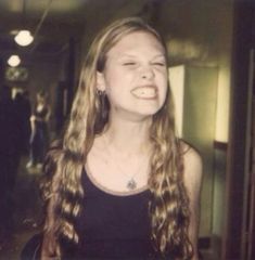 a young woman with long hair standing in front of a mirror and smiling at the camera