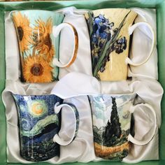 four coffee mugs in a green box with paintings on the sides and one has a sunflower