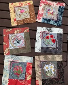 four square quilts with different designs on them sitting on a wooden table next to each other