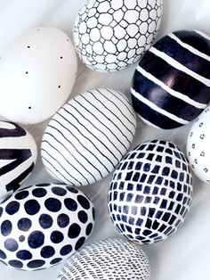 an assortment of painted easter eggs on a white surface with black and white designs around them