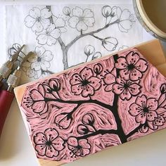 a pink and black flowered painting on a piece of paper next to some crafting supplies