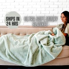 a woman sitting on a couch under a blanket with the words, ultra soft minky blanket