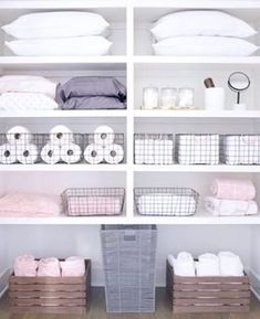 an organized closet with white shelving and linens in baskets on the bottom shelf