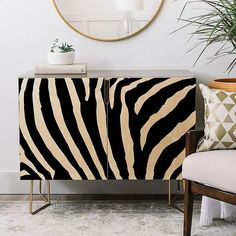 a zebra print cabinet next to a chair and potted plant