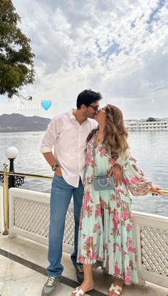 a man and woman standing next to each other near the water