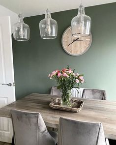 a dining room table with chairs and a clock on the wall