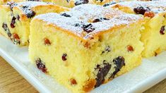 several pieces of cake on a white plate with powdered sugar and raisins