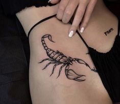 a scorpion tattoo on the side of a woman's stomach, with black ink