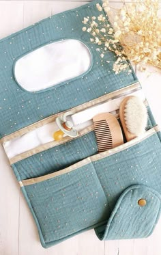 a blue bag with some items in it on a white table next to a brush and comb