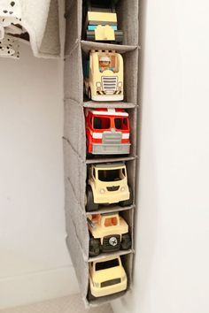 a toy car storage unit in the corner of a white room with toys on it