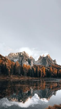 the mountains are covered in autumn foliage and reflected in the still water on the lake