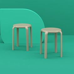 two small stools sitting next to each other in front of a green wall,