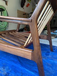 a wooden rocking chair sitting on top of a blue floor next to a green hose