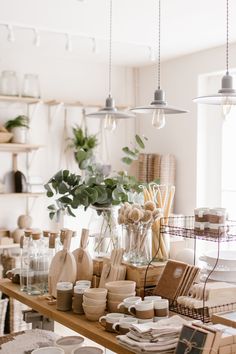 a table topped with lots of cups and vases filled with flowers next to shelves