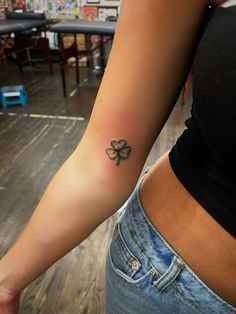 a woman with a four leaf clover tattoo on her arm