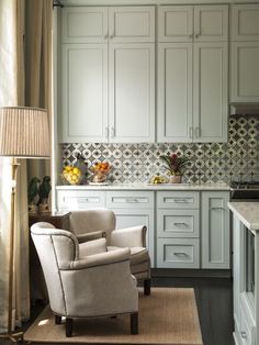 a living room filled with furniture next to a kitchen counter top and white cupboards