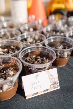 there are many desserts in plastic cups with dirt on the top and one has a sign that says dirt piles