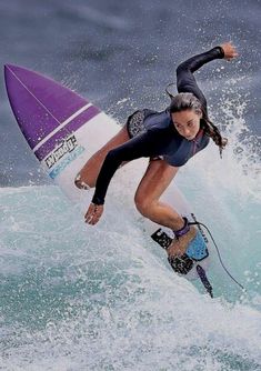 a woman riding a wave on top of a purple and white surfboard in the ocean