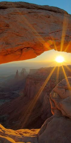 the sun is shining through an arch in the desert