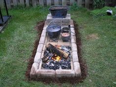 a fire pit in the middle of a yard with pots and pans on it