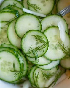 cucumber slices are arranged in a bowl with dill on the side and a fork sticking out of them